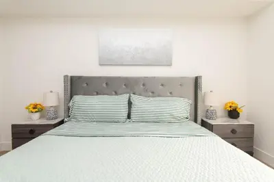 a white bedroom with a large bed with two night stands at By The Coast Living in Santa Monica Pier Promenade in Los Angeles