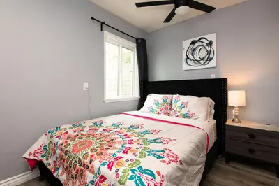 a bedroom with a bed with a colorful comforter and a window at 3bedroom 2bath Unit complementary parking onsite in Los Angeles