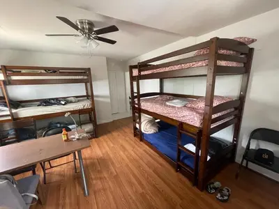 a room with bunk beds and a table and a ceiling fan at Females room bunk beds in Los Angeles