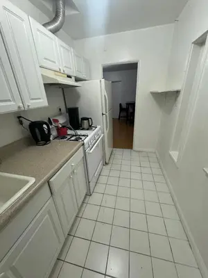 a kitchen with white cabinets and a white tiled floor at Females room bunk beds in Los Angeles