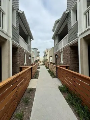 a sidewalk between two buildings with wooden fences at HelloLA in Whittier
