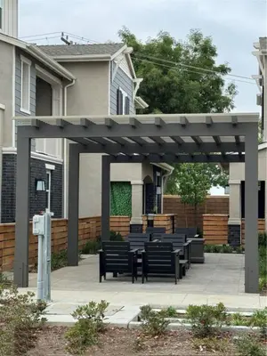 a pergola with benches and tables in front of a house at HelloLA in Whittier