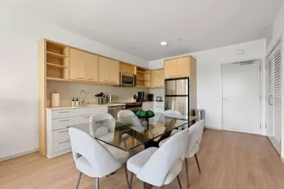 a kitchen with a glass table and white chairs at Emerald Ridge - Luxe Hollywood Walk of Fame in Los Angeles