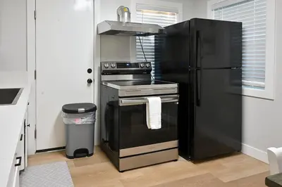 a kitchen with a black refrigerator and a stove at Relaxing Cozy Back House with Backyard in Upland