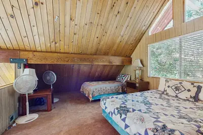 a bedroom with two beds in a room with wooden ceilings at Villa Elvira in Lake Arrowhead