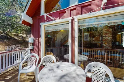 a porch with white chairs and a table and a window at Villa Elvira in Lake Arrowhead