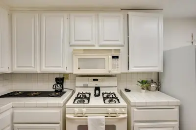 a white kitchen with a stove and a microwave at 12 Mi to Dtwn LA Family Home with Patio and Yard! in Downey
