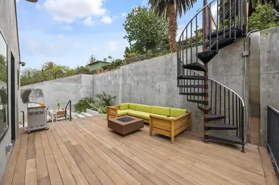 a patio with a green couch and a staircase at New Listing Hillside Villa by Colby & Conrad in Los Angeles