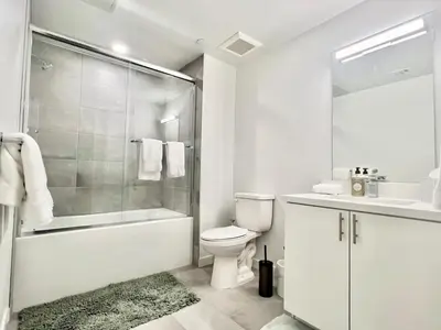 a white bathroom with a shower toilet and a sink at Designer 1 Bedroom Condo in Silver Lake in Los Angeles