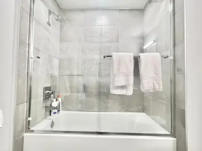 a bathroom with a tub and a shower with towels at Designer 1 Bedroom Condo in Silver Lake in Los Angeles