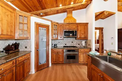 a kitchen with wooden cabinets and a stove top oven at California Dreaming: Lakeside Cabin Getaway in the Best Location in San Bernardino