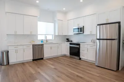 a white kitchen with white cabinets and a refrigerator at New 2BR Family Home Nr Universal in Gemco
