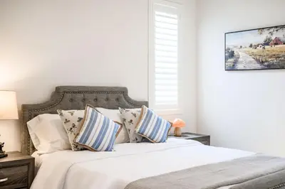 a bedroom with a white bed with blue and white pillows at Spacious 5BR Getaway w Game Room & Modern Comfort in Fontana