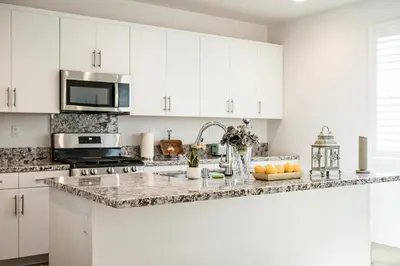 a kitchen with white cabinets and a granite counter top at Spacious 5BR Getaway w Game Room & Modern Comfort in Fontana