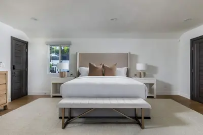 a white bedroom with a large bed and a bench at Villa Incanto in Los Angeles
