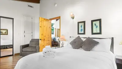 a bedroom with a large white bed and a chair at The Fairway Hideaway by AvantStay Game Room Outdoor Dining Near Lake Arrowhead in Lake Arrowhead
