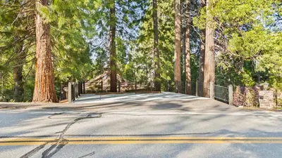 a road with a fence and some trees at The Fairway Hideaway by AvantStay Game Room Outdoor Dining Near Lake Arrowhead in Lake Arrowhead
