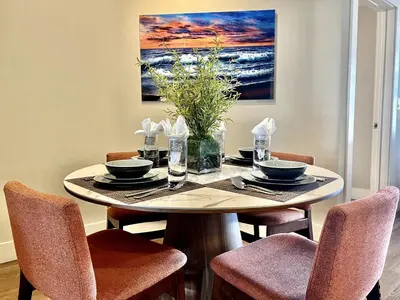 a dining room table with chairs and a painting on the wall at Designer 2 Bedroom with 3 Beds- Pool View, Gym, Parking in Los Angeles