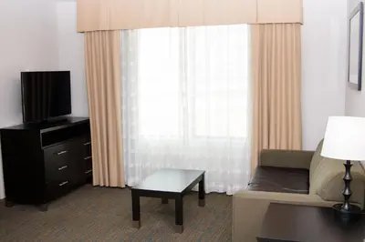 a living room with a couch and a tv and a table at Holiday Inn Express & Suites Bakersfield Airport by IHG in Bakersfield