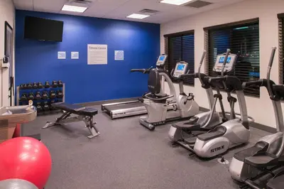 a gym with cardio equipment and a blue wall at Holiday Inn Express & Suites Bakersfield Airport by IHG in Bakersfield