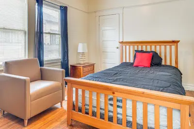 a bedroom with a bed with a red pillow and a chair at 2 Mi to USC Central Home in Los Angeles! in Los Angeles
