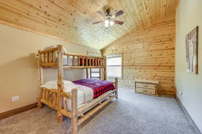 a log cabin bedroom with a bunk bed and a ceiling fan at Walkable Big Bear Lake Home with Private Hot Tub! in Big Bear Lake