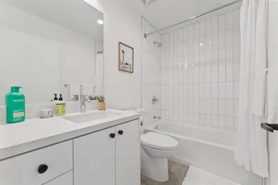 a white bathroom with a toilet and a tub and a sink at Stylist Downtown LA Gateway- Studio Apt in Los Angeles