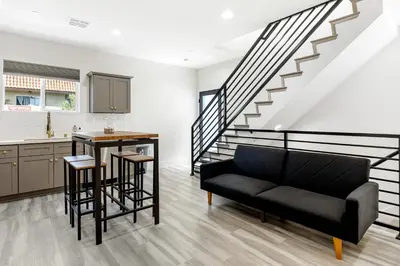 a living room with a black couch and a staircase at Contemporary Retreat Hollywood & DTLA in Los Angeles