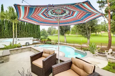 a patio with chairs and an umbrella next to a pool at Golf, Swim, Relax Family Retreat in Corona! in Corona