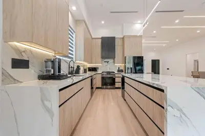 a large kitchen with white counter tops and wooden cabinets at The Valley Nest Backyard Gameroom in Los Angeles