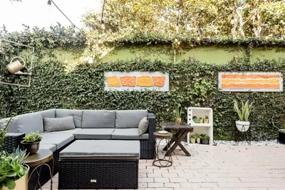 a patio with a couch in front of a green wall at Silver Triangle Oasis with Verdant Backyard in Los Angeles