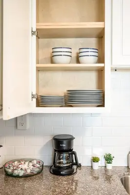 a kitchen counter with a coffee maker and plates in a cupboard at 1 Block to Beach Heaven Chic 2BD in Manhattan Beach