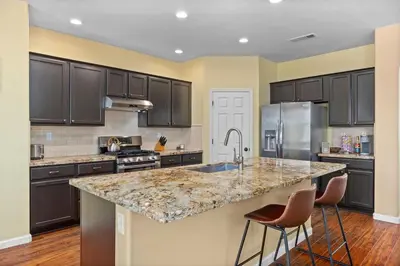 a kitchen with black cabinets and a granite counter top at Luxury Gated Retreat Golf Course Views Sleeps 8 in Bakersfield