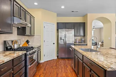 a kitchen with a stainless steel refrigerator and wooden floors at Luxury Gated Retreat Golf Course Views Sleeps 8 in Bakersfield