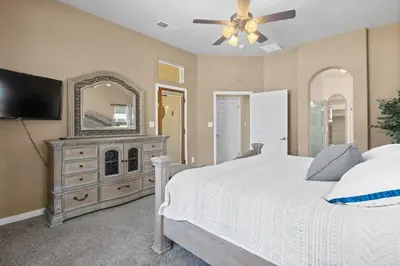 a bedroom with a bed and a dresser with a mirror at Spacious 4BR 3BA Home KING Suite Pool Sleeps 8 in Bakersfield
