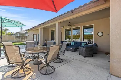 a patio with a table and chairs and an umbrella at Spacious 4BR 3BA Home KING Suite Pool Sleeps 8 in Bakersfield