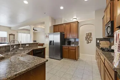 a kitchen with wooden cabinets and a stainless steel refrigerator at Stylish Silver Falls 4BR KING Master Game Room in Bakersfield