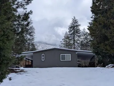 a house with snow in front of it at Peaceful Pines Place, a cozy mountain hideaway wAC