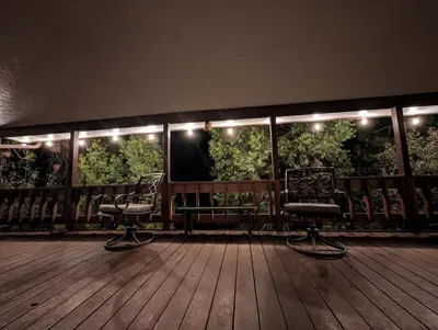 two chairs sitting on a deck with lights at Peaceful Pines Place, a cozy mountain hideaway wAC