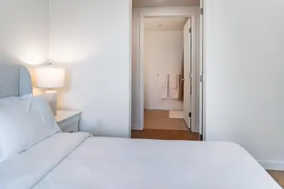 a bedroom with a white bed and a hallway at Luxury 2 Bedroom 2 Bathroom Residence With Fitness and Outdoor Pool in Los Angeles