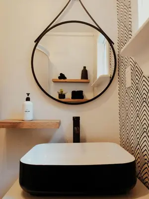 a bathroom with a round mirror and a white sink at Little Wolf Lodge Modern Cabin at Lake Gregory in Crestline