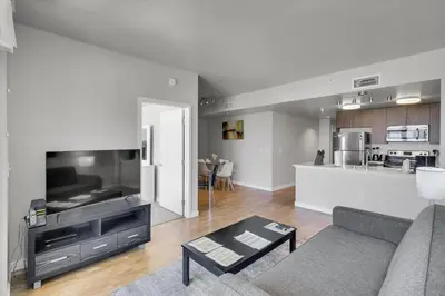 a living room with a couch and a tv and a kitchen at Global Luxury Suites in LA's Seaside in Los Angeles