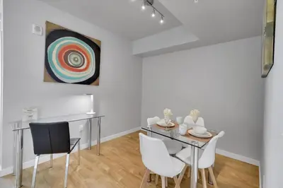 a dining room with a table and chairs and a painting at Global Luxury Suites in LA's Seaside in Los Angeles