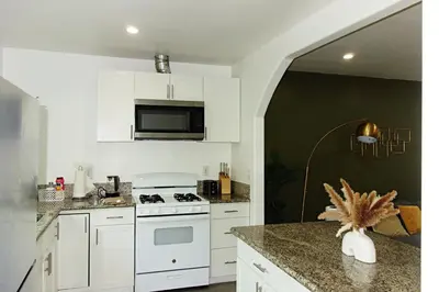 a kitchen with white cabinets and a white stove top oven at Casa Mid City - Centrally Located 1BR Getaway with Private Yard in Los Angeles