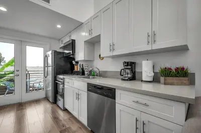 a kitchen with white cabinets and stainless steel appliances at Chic 1 Bedroom Loft with Balcony Hollywood Sign View Free Gated Parking Full Kitchen in Los Angeles