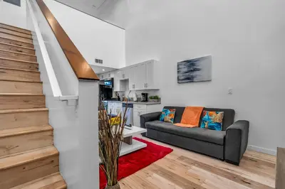 a living room with a couch and a kitchen at Chic 1 Bedroom Loft with Balcony Hollywood Sign View Free Gated Parking Full Kitchen in Los Angeles
