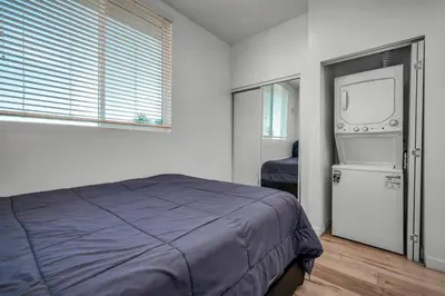 a bedroom with a bed and a refrigerator and a window at Koreatown Hollywood Urban Oasis 1 Bedroom Loft with Private Parking and Balcony in Los Angeles