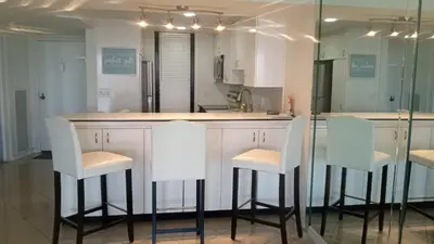 a kitchen with two white bar stools and a counter at A Stunning Luxury Resort-Style Furnished Condominium Plus All Inclusive Amenities! in Los Angeles
