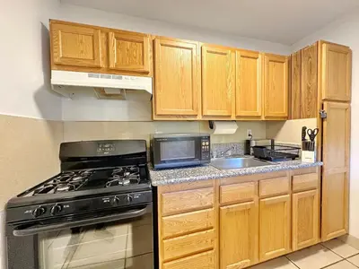 a kitchen with wooden cabinets and a stove and a sink at Relaxed and Cozy Poolside Studio - LOU2 - BUR in Burbank