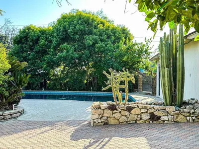 a stone wall next to a swimming pool with cactus at Relaxed and Cozy Poolside Studio - LOU2 - BUR in Burbank